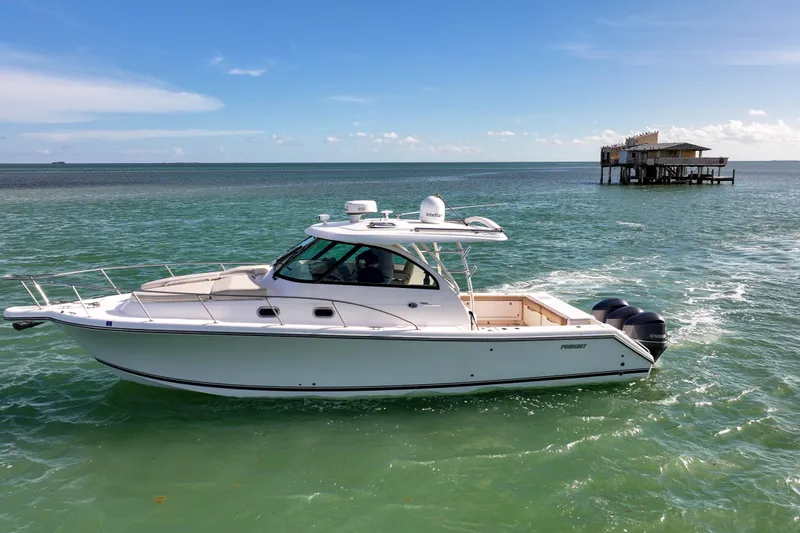  Yacht Photos Pics 2016 Pursuit OS 385 Offshore boat cruising on turquoise waters near a coastal structure.