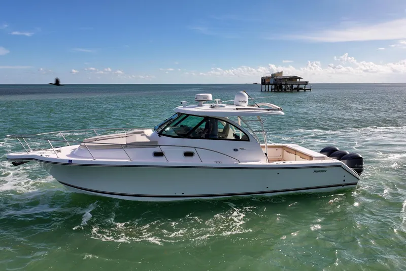  Yacht Photos Pics 2016 Pursuit OS 385 Offshore boat cruising on open water, with a distant structure.