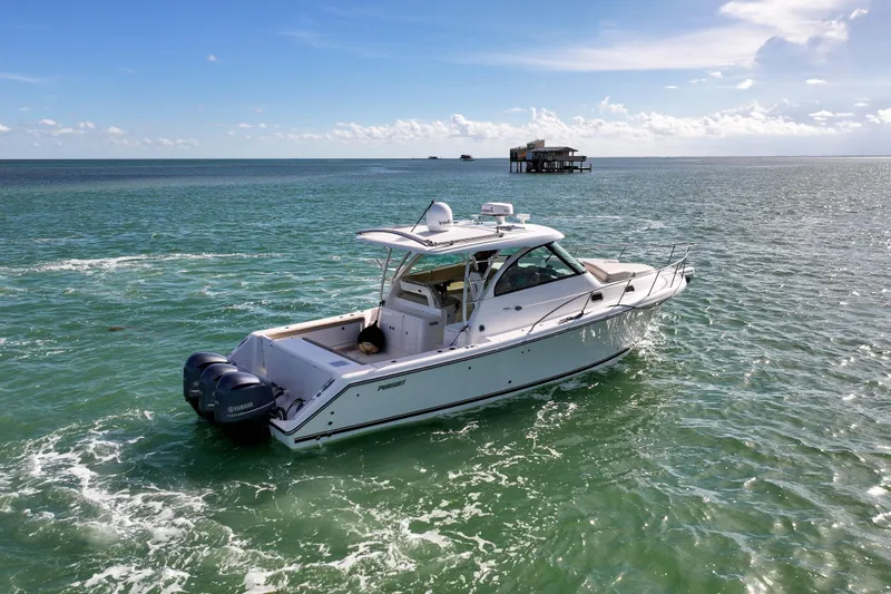  Yacht Photos Pics 2016 Pursuit OS 385 Offshore boat cruising on open water under a clear blue sky.
