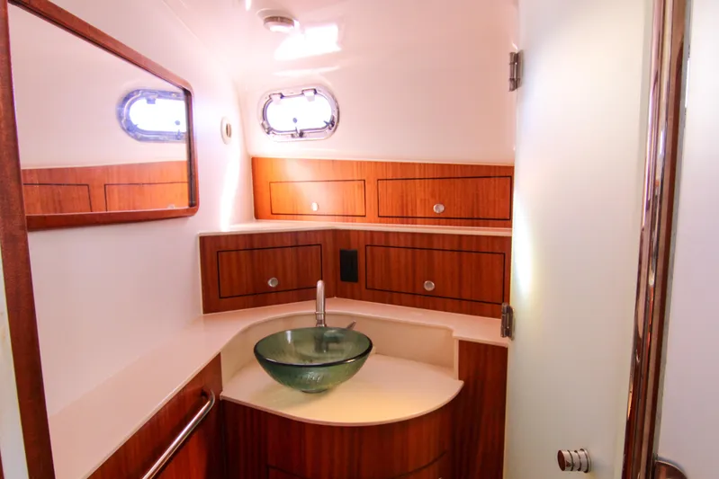  Yacht Photos Pics Luxurious bathroom in 2016 Pursuit OS 385 Offshore boat with glass sink and wooden cabinetry.