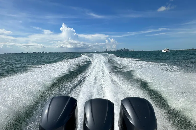  Yacht Photos Pics 2016 Pursuit OS 385 Offshore boat cruising with city skyline in the background.