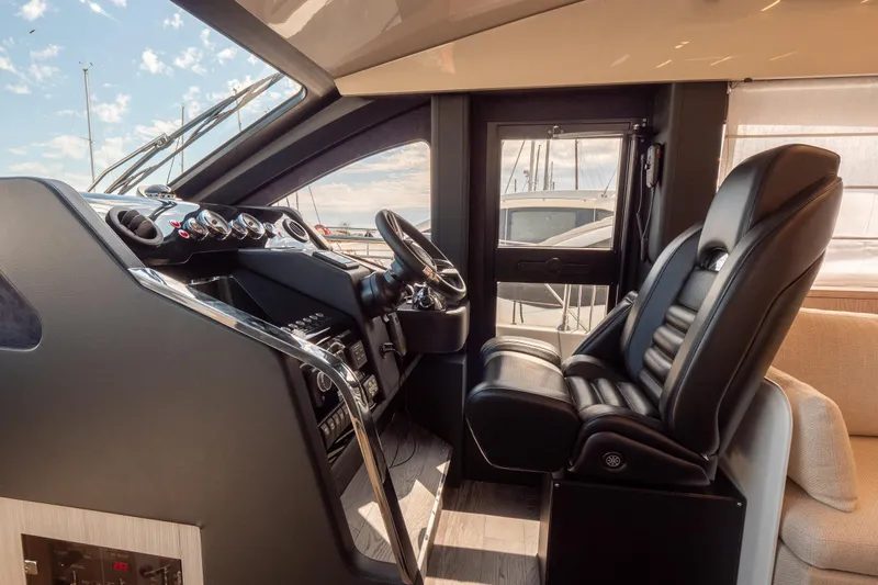 Curly Yacht Photos Pics Luxurious 2021 Cranchi E52S yacht cockpit with sleek black leather seating and modern controls.