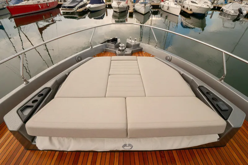 Curly Yacht Photos Pics 2021 Cranchi E52S yacht with spacious sunbed on teak deck, docked in marina.