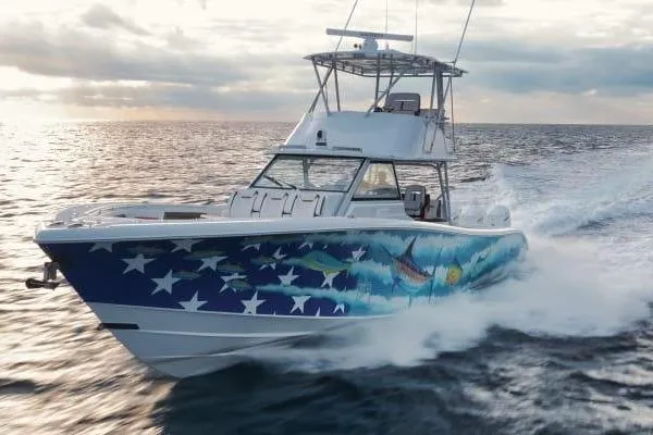  Yacht Photos Pics 2022 Yellowfin 54 Offshore boat with vibrant marine-themed hull design cruising on open water.