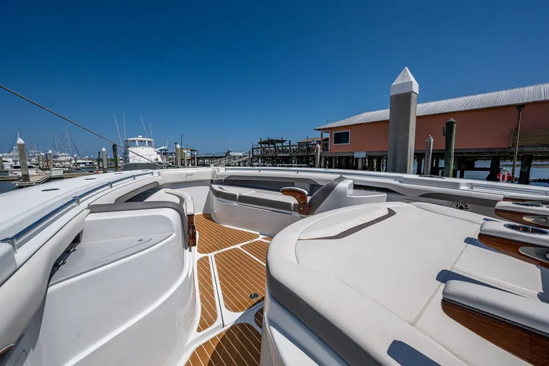  Yacht Photos Pics 2022 Yellowfin 54 Offshore boat interior with luxurious seating and wooden deck at marina.