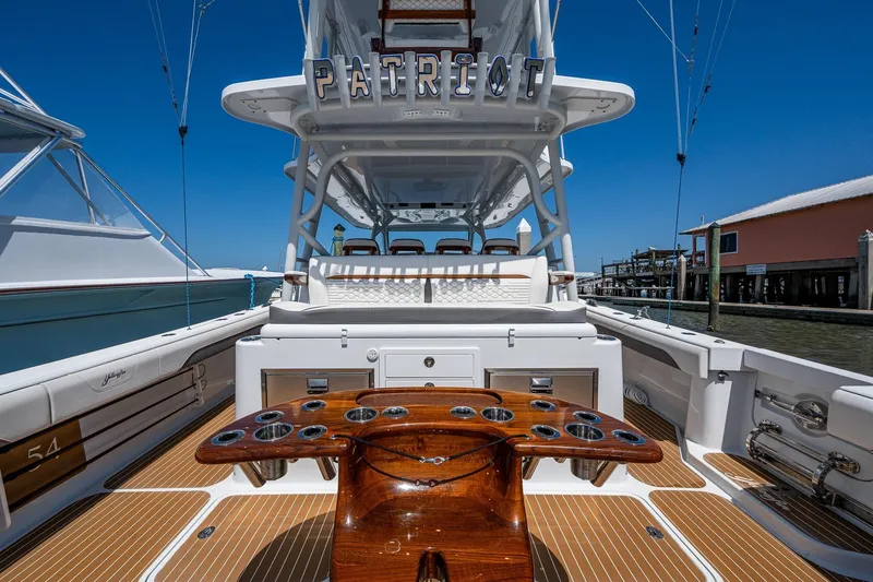  Yacht Photos Pics 2022 Yellowfin 54 Offshore boat with fishing rod holders and seating, docked under clear blue sky.
