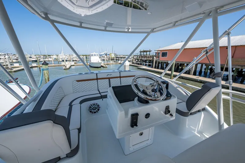  Yacht Photos Pics 2022 Yellowfin 54 Offshore boat helm with marina view, featuring modern seating and steering.