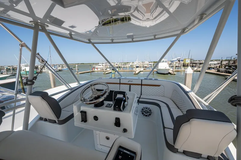  Yacht Photos Pics 2022 Yellowfin 54 Offshore boat helm with marina view, featuring modern steering and seating.