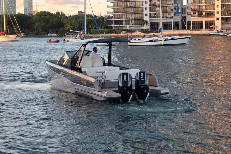 Virtue Yacht Photos Pics 2026 Virtue V10 boat cruising in a marina with modern buildings in the background.