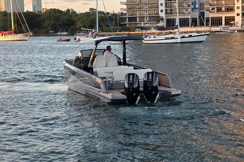 Virtue Yacht Photos Pics 2026 Virtue V10 boat cruising on a scenic waterfront with modern buildings.