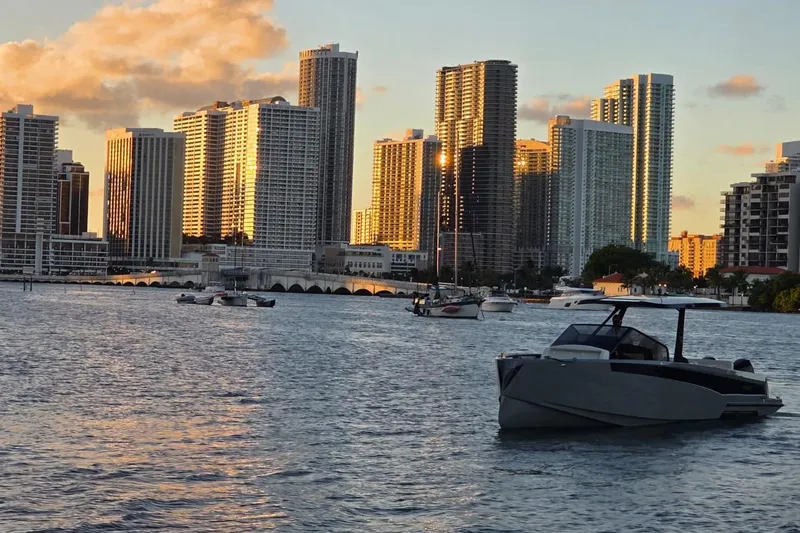 Virtue Yacht Photos Pics Modern city skyline at sunset with boats, featuring a 2026 Virtue V10.