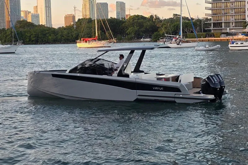 Virtue Yacht Photos Pics 2026 Virtue V10 luxury boat cruising on a scenic waterfront with city skyline.