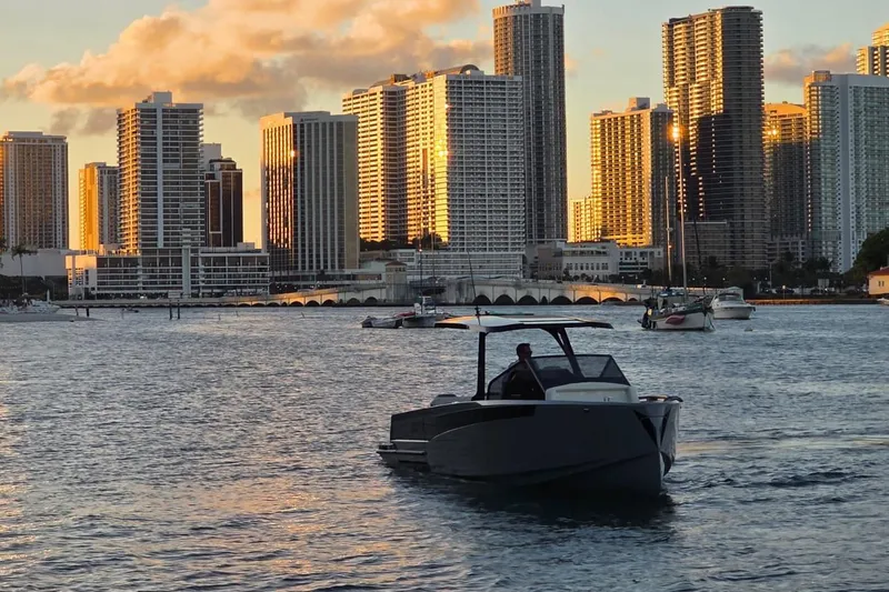 Virtue Yacht Photos Pics Modern Virtue V10 boat cruising near city skyline at sunset, 2026 model.