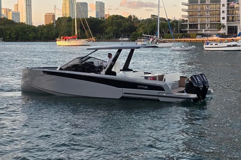 Virtue Yacht Photos Pics 2026 Virtue V10 luxury boat cruising on a scenic waterfront with city skyline.