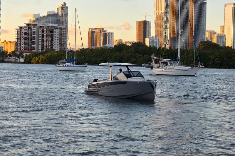 Virtue Yacht Photos Pics 2026 Virtue V10 boat cruising on a scenic urban waterway with city skyline.