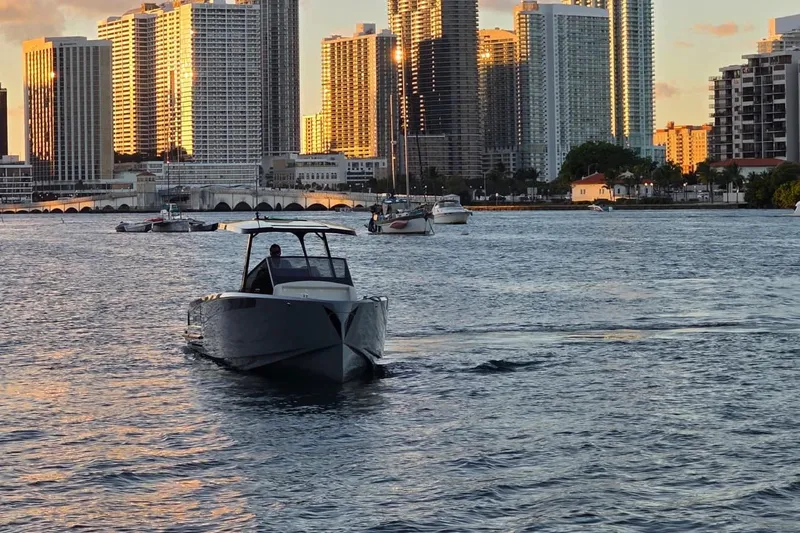 Virtue Yacht Photos Pics Boat cruising near city skyline at sunset, featuring 2026 Virtue V10 model.