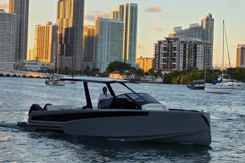 Virtue Yacht Photos Pics 2026 Virtue V10 yacht cruising in urban waterfront with skyscrapers in background.