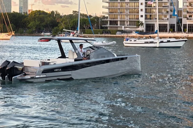Virtue Yacht Photos Pics 2026 Virtue V10 boat cruising in a scenic waterfront setting with modern buildings.