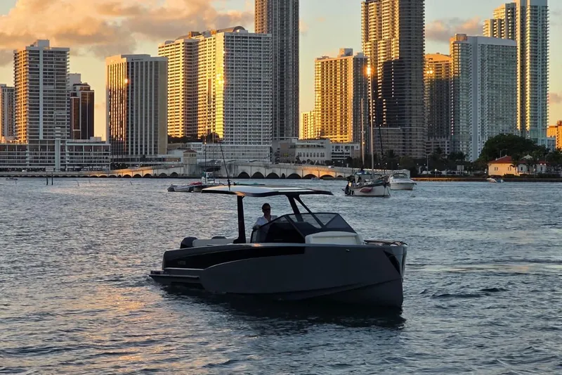 Virtue Yacht Photos Pics 2026 Virtue V10 boat cruising near city skyline at sunset.
