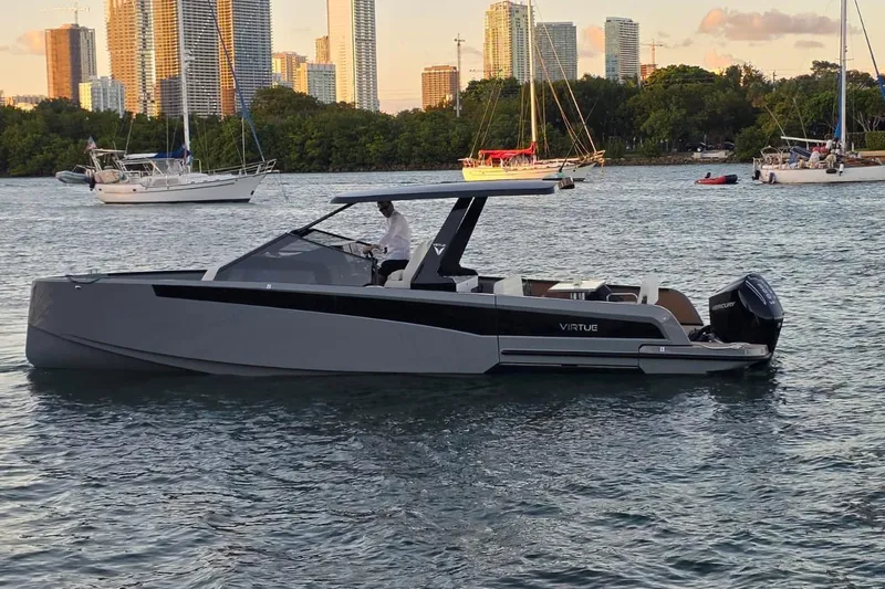 Virtue Yacht Photos Pics 2026 Virtue V10 boat cruising on a scenic waterway with city skyline backdrop.