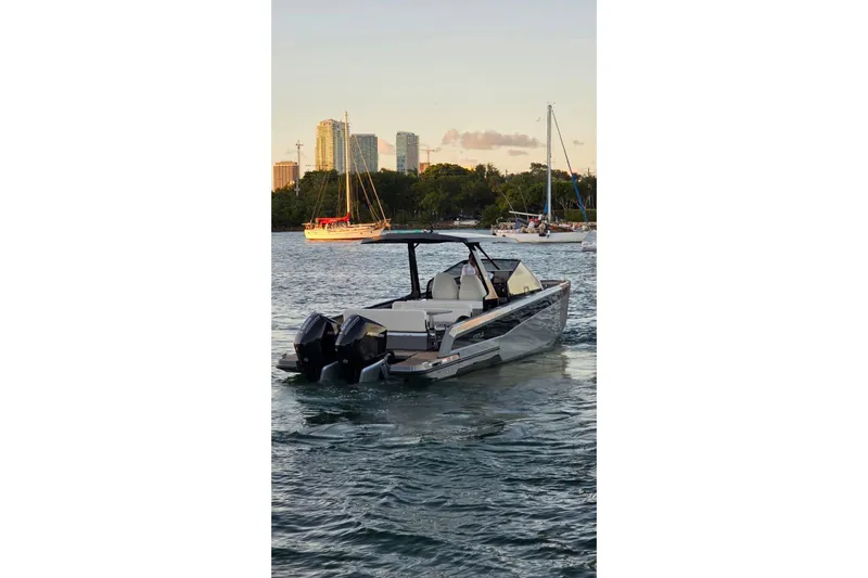 Virtue Yacht Photos Pics Modern 2026 Virtue V10 boat cruising on a scenic waterway with city skyline backdrop.