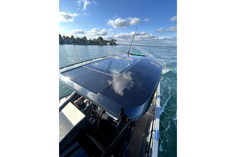 Virtue Yacht Photos Pics Futuristic 2026 Virtue V10 yacht cruising on a sunny day, reflecting clouds on its sleek roof.