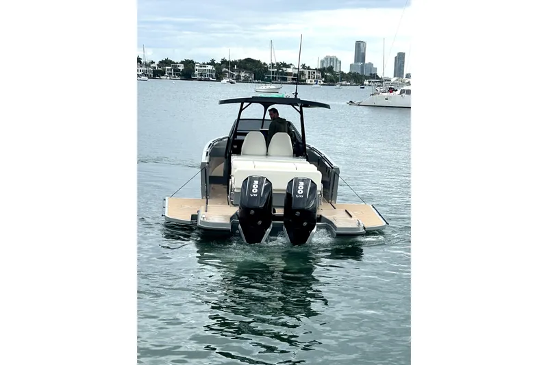 Virtue Yacht Photos Pics 2026 Virtue V10 boat with dual engines on calm water, city skyline in background.