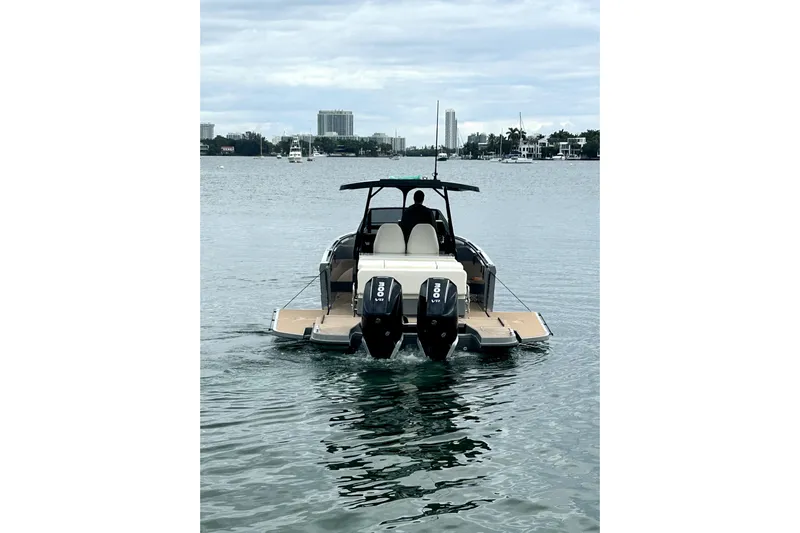 Virtue Yacht Photos Pics 2026 Virtue V10 boat cruising on a calm waterway with cityscape in background.