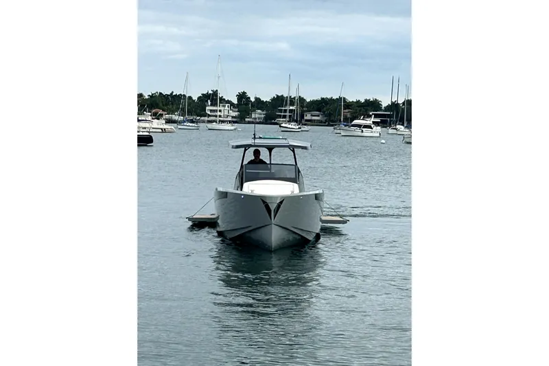 Virtue Yacht Photos Pics 2026 Virtue V10 boat cruising in a marina with other vessels in the background.