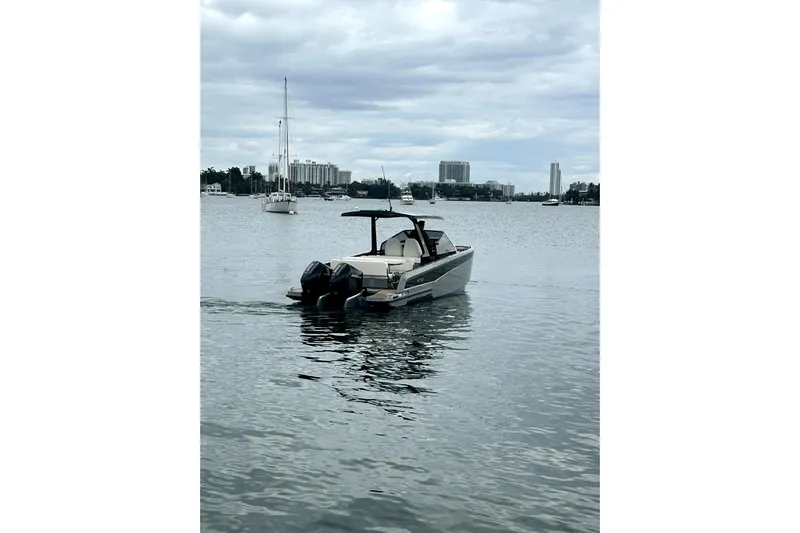 Virtue Yacht Photos Pics 2026 Virtue V10 boat on calm water with city skyline in background.