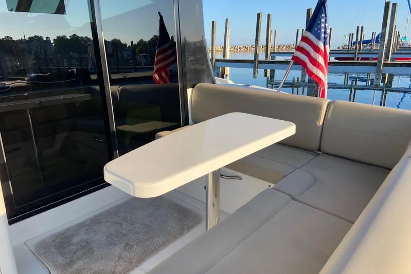 Godsend Yacht Photos Pics 2015 Sea Ray 470 Sundancer yacht with elegant seating and table, docked with American flag.