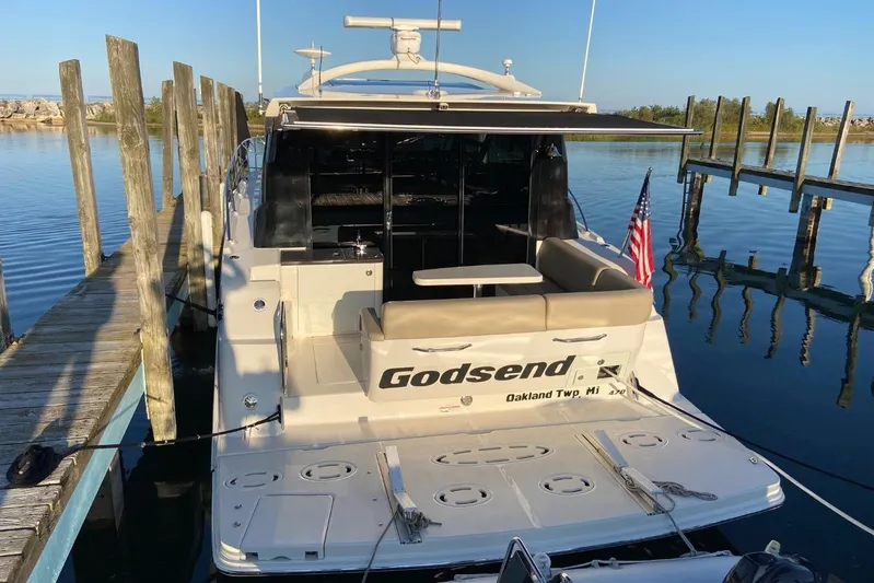 Godsend Yacht Photos Pics 2015 Sea Ray 470 Sundancer docked, rear view with seating and American flag.