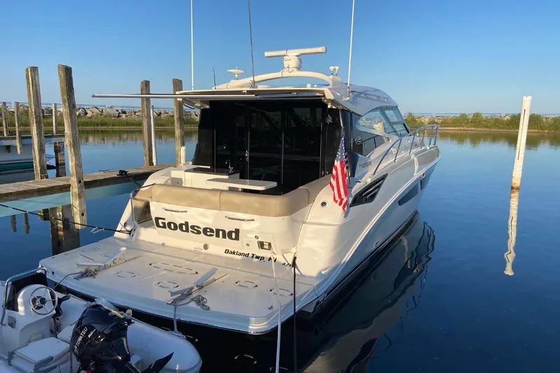 Godsend Yacht Photos Pics 2015 Sea Ray 470 Sundancer yacht docked, displaying American flag, calm water reflection.