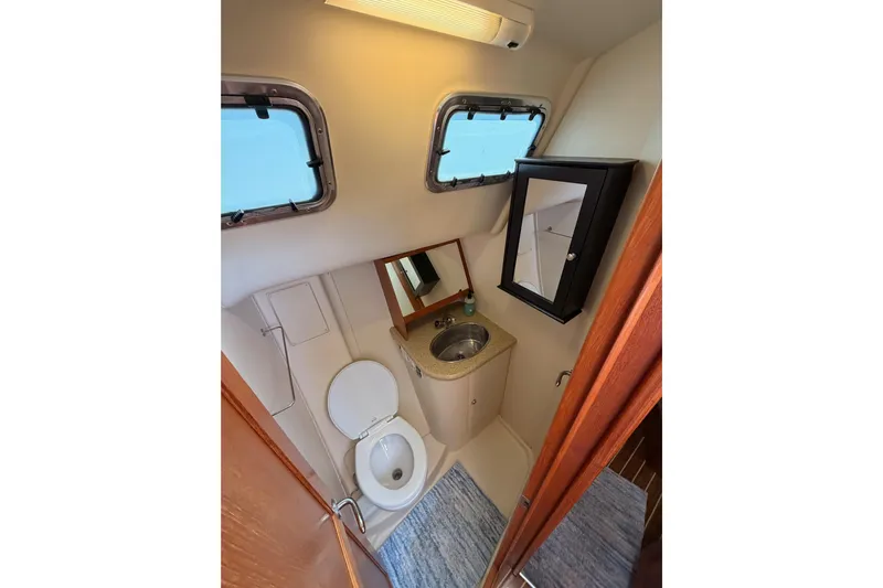 Wailele Yacht Photos Pics Compact bathroom in 2007 Hunter 44 Deck Salon yacht with sink, toilet, and mirror cabinet.
