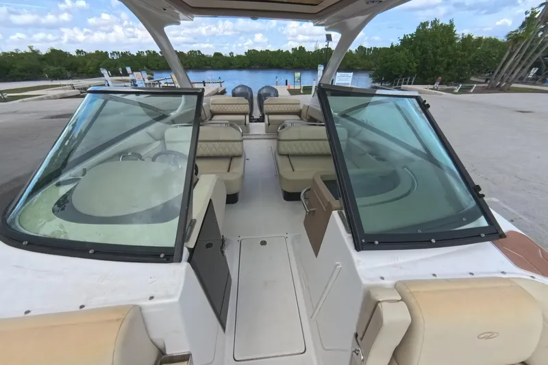  Yacht Photos Pics 2018 Regal 29 OBX boat interior with seating and windshield, docked by a scenic waterway.