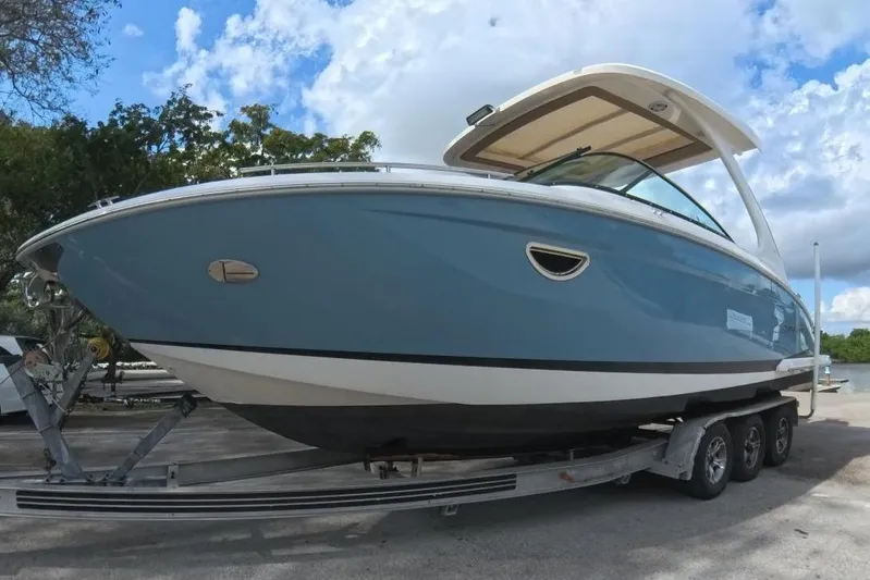  Yacht Photos Pics 2018 Regal 29 OBX boat on trailer, parked near water under a cloudy sky.