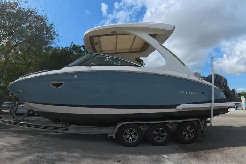  Yacht Photos Pics 2018 Regal 29 OBX boat on trailer, parked beside a truck under a cloudy sky.