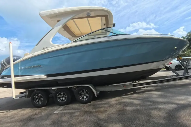  Yacht Photos Pics 2018 Regal 29 OBX boat on trailer, blue hull, parked outdoors under blue sky.
