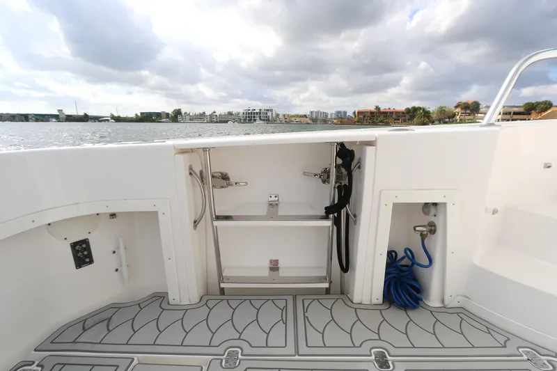  Yacht Photos Pics 2012 Intrepid 475 Sport Yacht deck with storage compartments and water hose, overlooking calm waters.