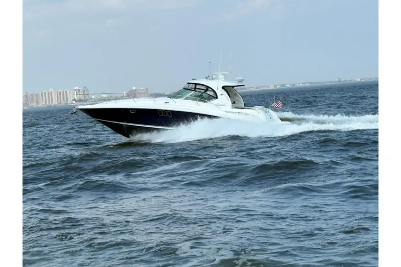  Yacht Photos Pics 2006 Sea Ray 44 Sundancer cruising on open water with city skyline in background.