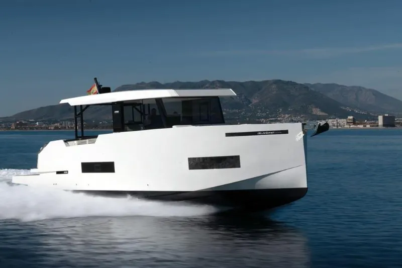  Yacht Photos Pics 2025 De Antonio Yachts D50 cruising on water with mountainous backdrop.