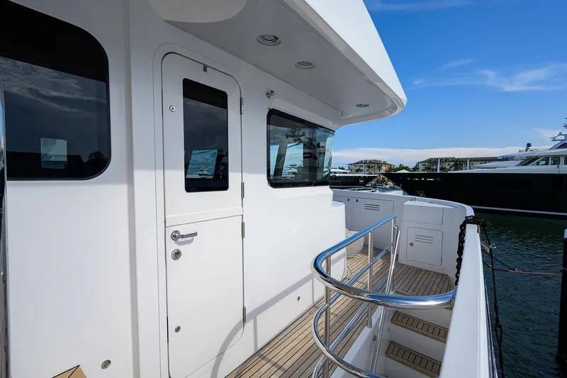 Lacey Kay Yacht Photos Pics Side deck view of a 2017 Nordhavn 96 yacht with white exterior and wooden flooring.