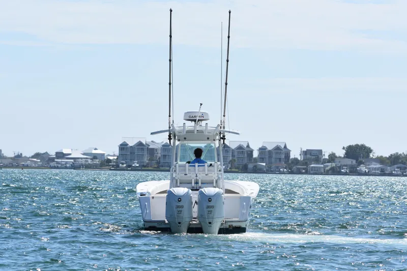  Yacht Photos Pics 2008 Regulator 32 Forward Seating boat cruising on a sunny day near coastal homes.