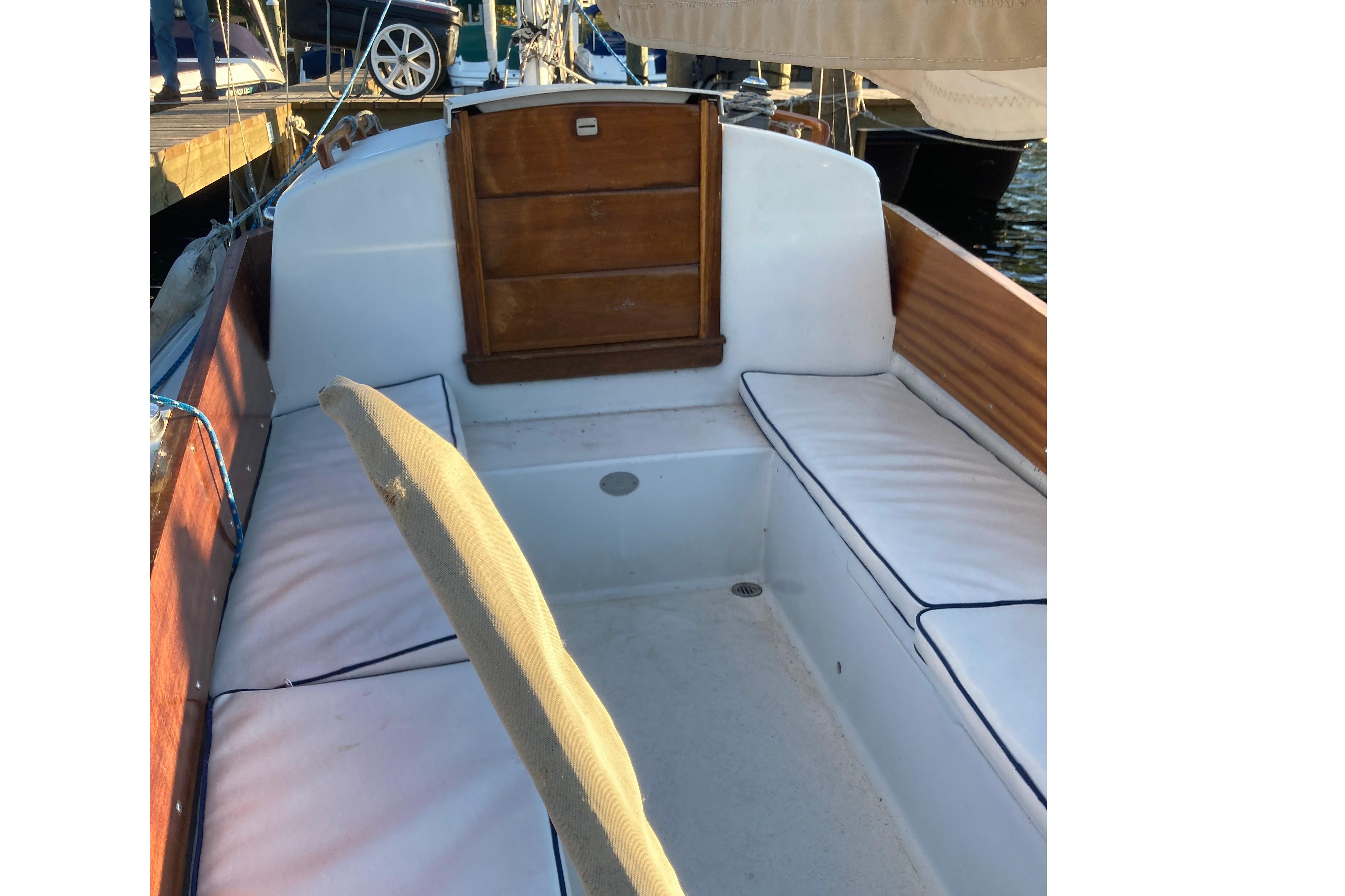 1964 Pearson Commander sailboat cockpit with white cushions and wooden accents.