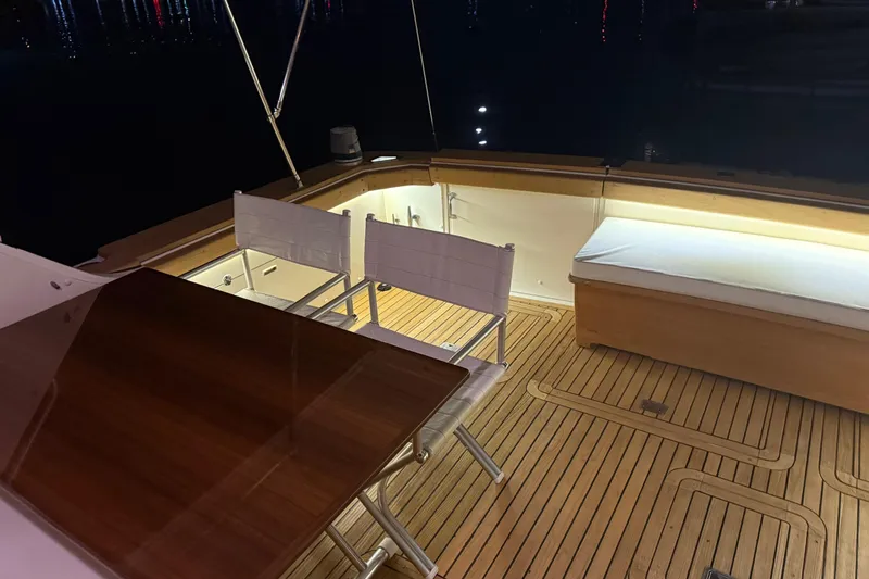  Yacht Photos Pics 1987 Bertram 37 Convertible yacht deck with chairs and wooden flooring at night.