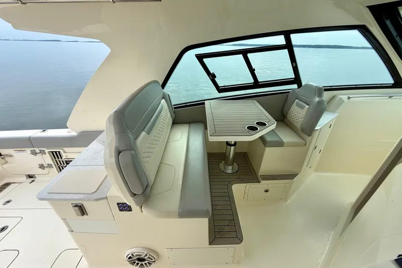 Yacht Photos Pics 2023 Scout 350 LXZ boat interior with seating and table, overlooking calm waters.