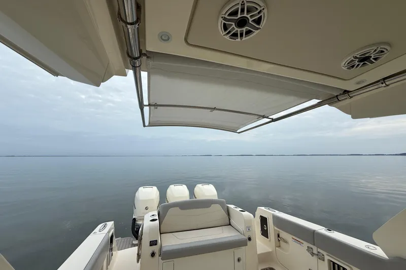  Yacht Photos Pics 2023 Scout 350 LXZ boat with canopy, overlooking calm waters.