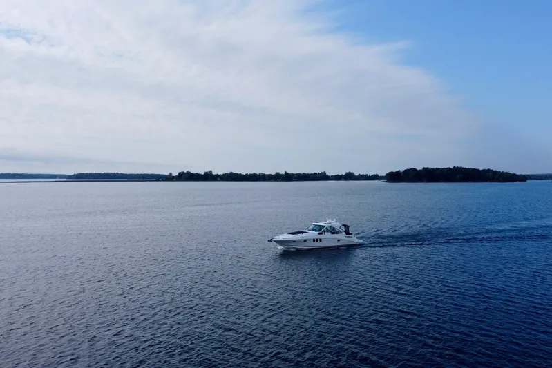  Yacht Photos Pics 2009 Sea Ray 48 Sundancer cruising on a calm, expansive lake under a cloudy sky.