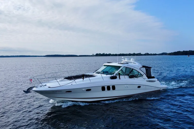  Yacht Photos Pics 2009 Sea Ray 48 Sundancer cruising on a calm, scenic lake under a partly cloudy sky.