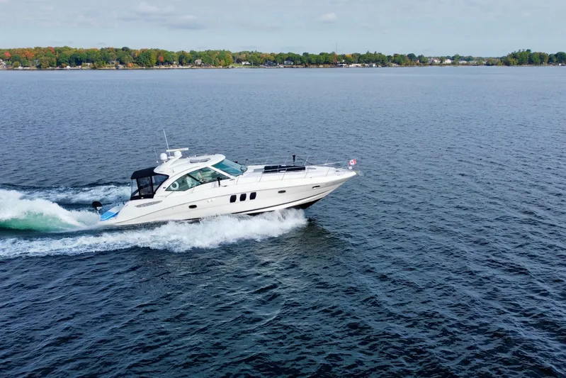  Yacht Photos Pics 2009 Sea Ray 48 Sundancer cruising on a calm lake with scenic shoreline.